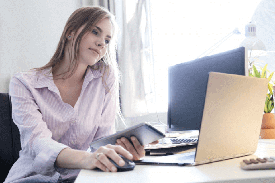 Mujer rubia sentada en su escritorio revisando en su laptop el curso de talento humano en línea