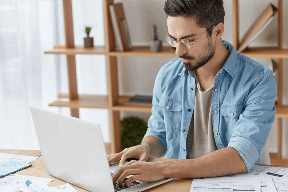 Imagen de un hombre sentado en su oficina y revisando en su laptop un curso en una plataforma elearning