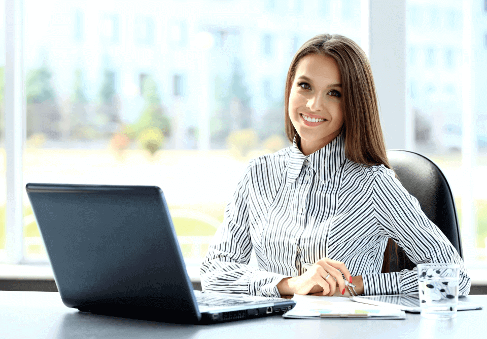 empresaria sonriente frente a laptop revisando el sistema del desempeño 