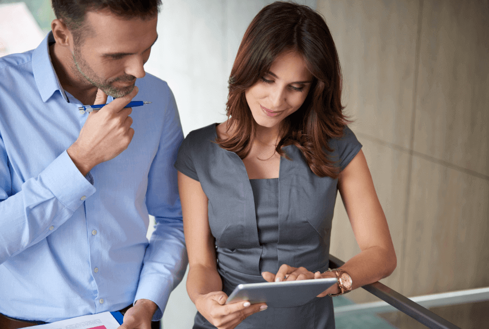Un hombre y una mujer en su oficina revisando el sistema de evaluación de desempeño en una tablet